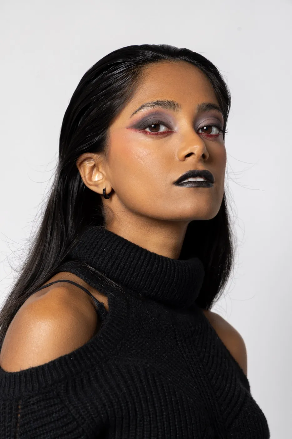Maquillage éditorial studio : lèvres noires et fards violets sur fond blanc