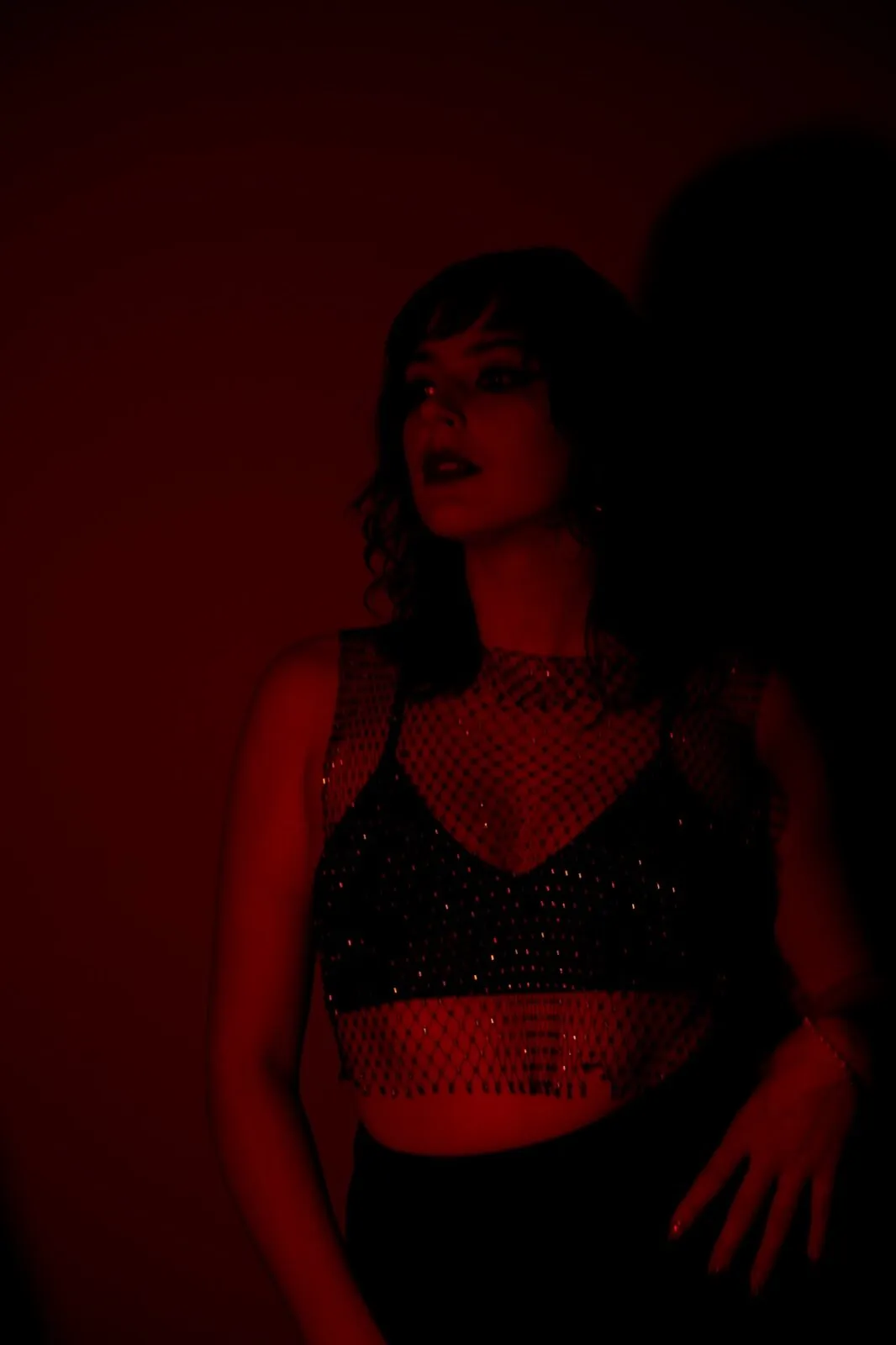 Portrait sous dominante rouge sombre, top résille pailleté